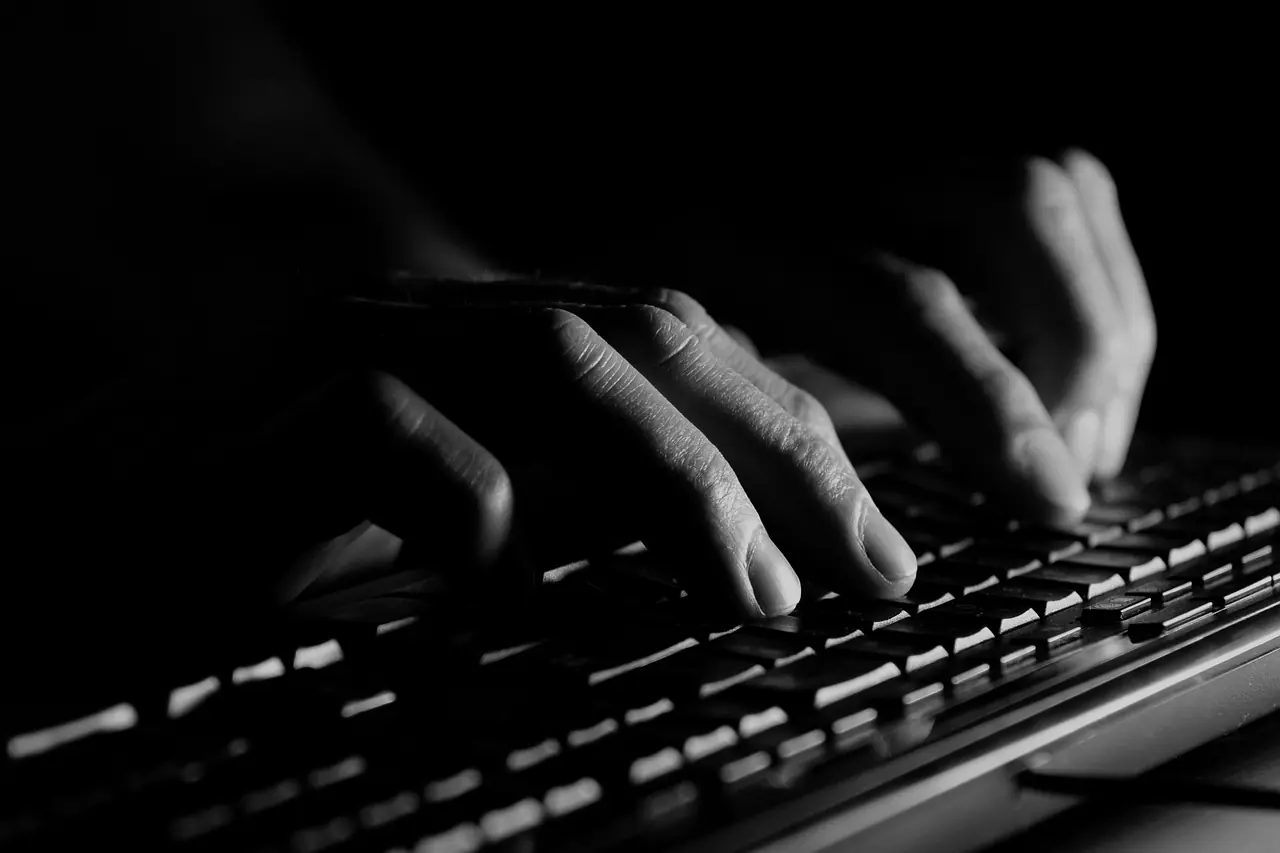 Hände tippen im Halbdunkel Angaben über eine Tastatur ab – FinDoku entlastet Mitarbeiter vom Abtippen
